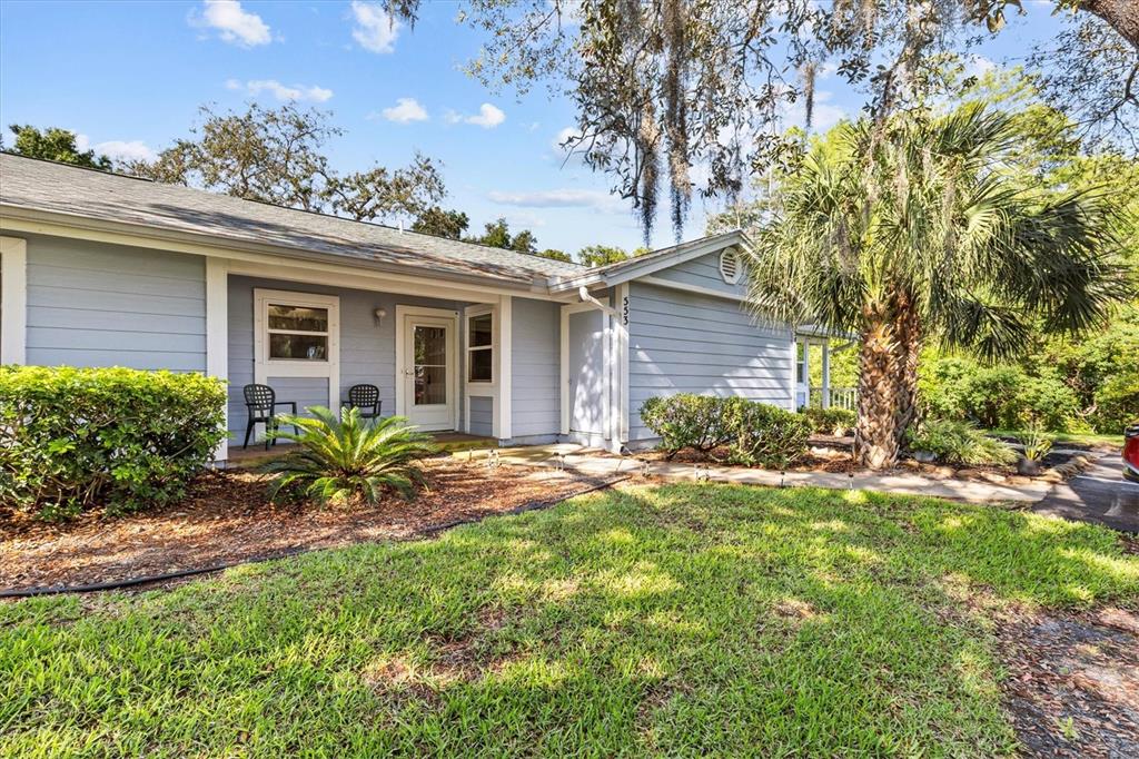 A light blue, single-story house with a front porch, lawn, and a palm tree — 39650 US HIGHWAY 19 N UNIT 553, TARPON SPRINGS, FL
