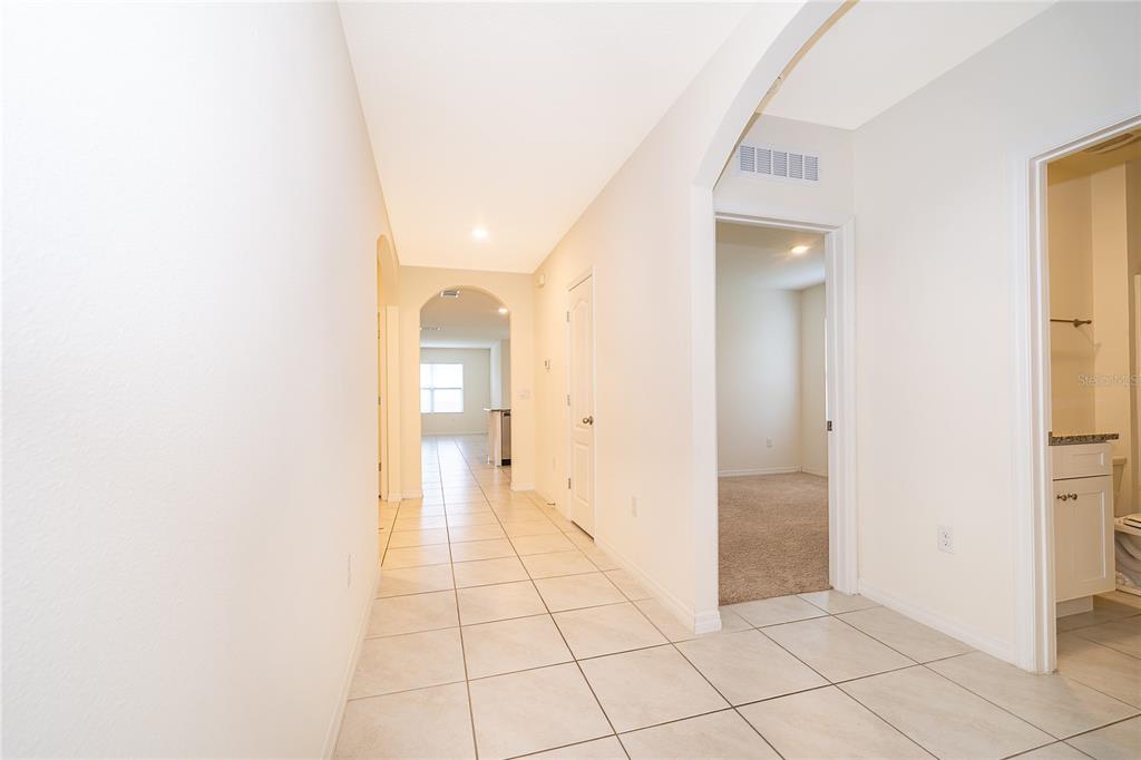 A tiled hallway leads to an arched entryway, a carpeted bedroom, and a bathroom — 5354 PALOMINO PLACE, APOPKA, FL