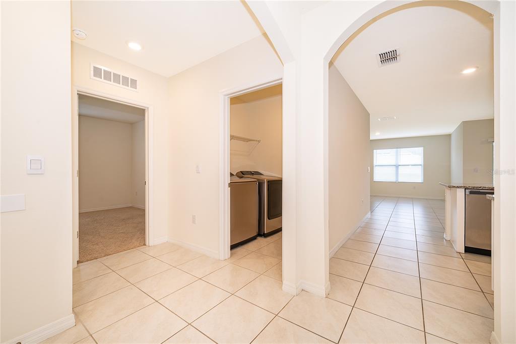 A tiled hallway leads to a laundry room, a carpeted bedroom, and an open kitchen area — 5354 PALOMINO PLACE, APOPKA, FL
