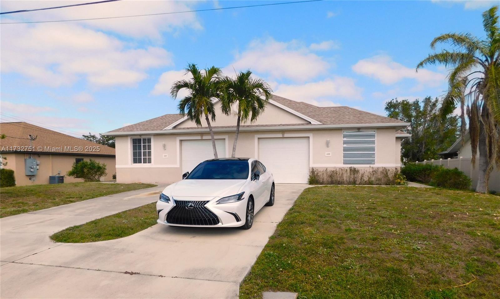 A white sedan is parked in the driveway of a single-story house with two garages — 617 SE 7 ST, Cape Coral FL 33990, CAPE CORAL, FL