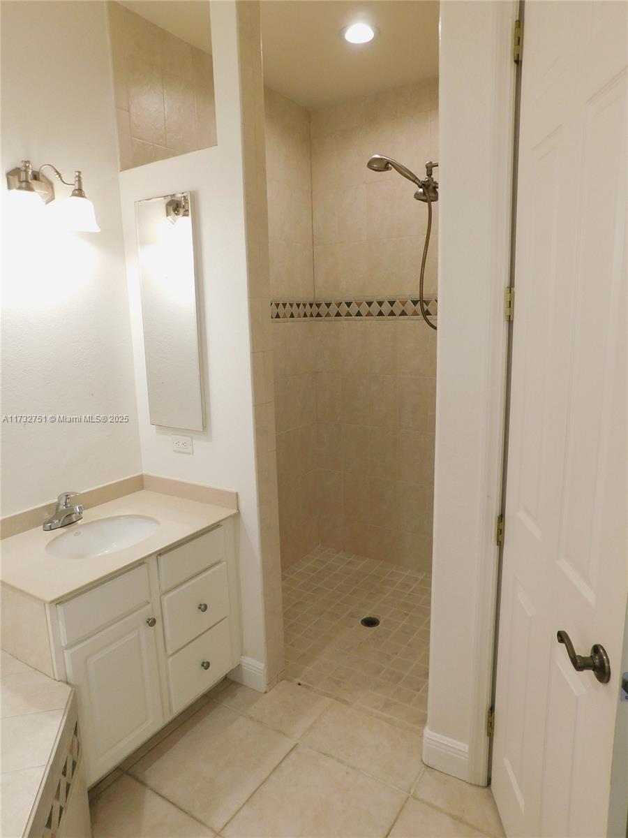 A bathroom features a white vanity, a tiled walk-in shower, and a closed door — 617 SE 7 ST, Cape Coral FL 33990, CAPE CORAL, FL