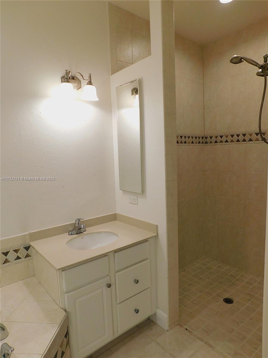A bathroom features a white vanity, a sink, a mirror, and a tiled walk-in shower — 617 SE 7 ST, Cape Coral FL 33990, CAPE CORAL, FL