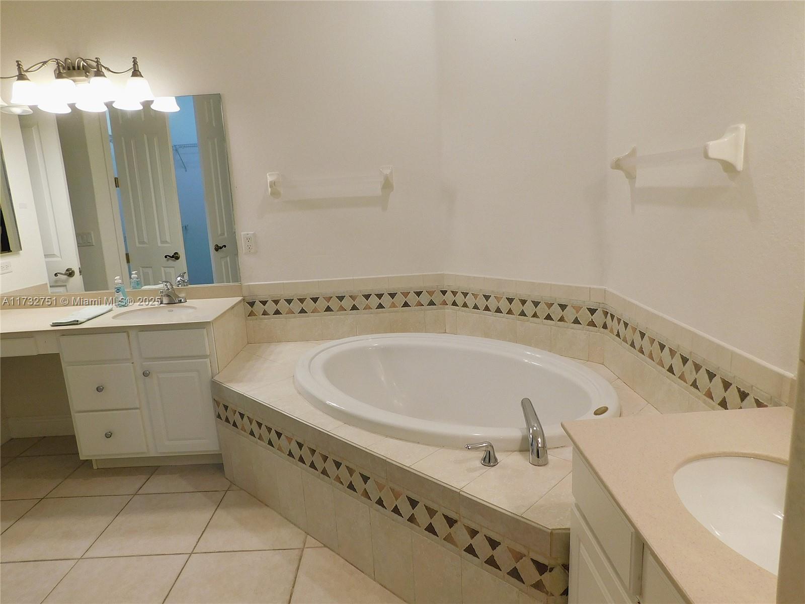A bathroom features a corner soaking tub with tile surround and dual white vanity sinks — 617 SE 7 ST, Cape Coral FL 33990, CAPE CORAL, FL