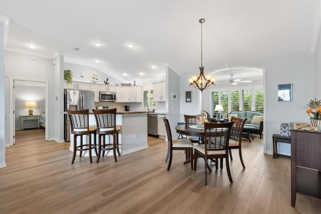 An open-concept kitchen and dining area featuring light wood floors and white cabinetry — 3394 RIDGEWOOD PATH, THE VILLAGES, FL