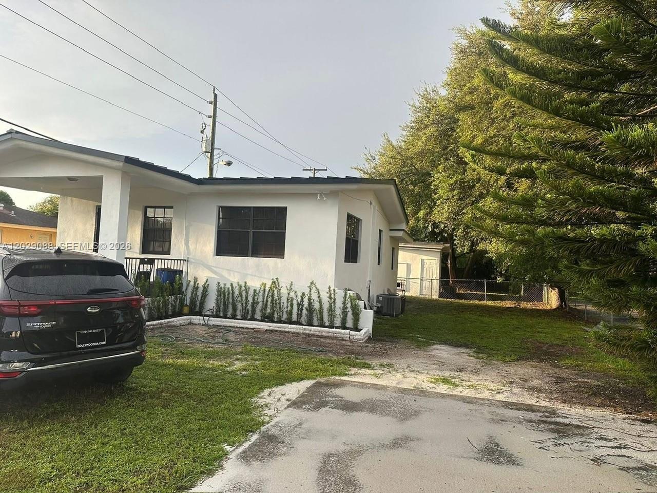 A white house with a carport and a side yard featuring a small shed — 2041 NW 100th St, Miami FL 33147, MIAMI, FL