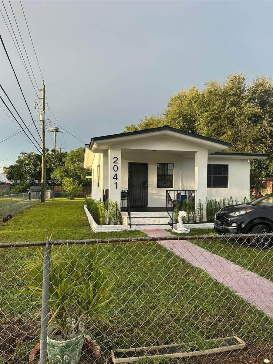 A white, single-story house with a front porch and a chain-link fence in the yard — 2041 NW 100th St, Miami FL 33147, MIAMI, FL