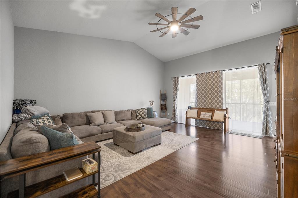 A living room features a large sectional sofa, a central ottoman, and a ceiling fan — 4525 SW 52ND CIRCLE UNIT 106, OCALA, FL