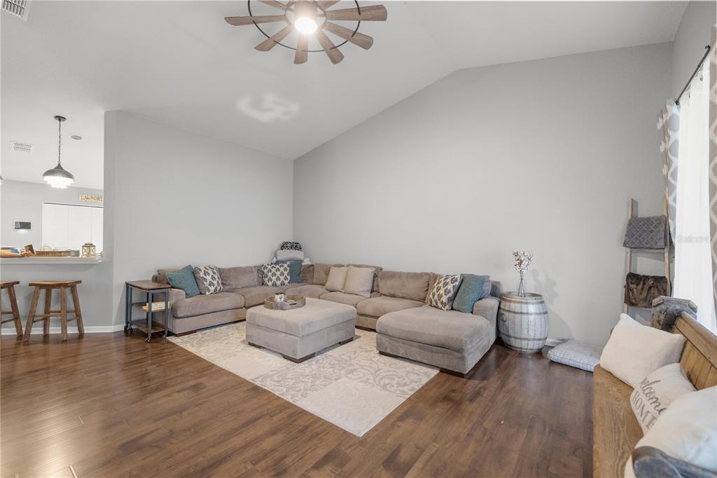 A living room features a large sectional sofa, a central ottoman, and wood flooring — 4525 SW 52ND CIRCLE UNIT 106, OCALA, FL