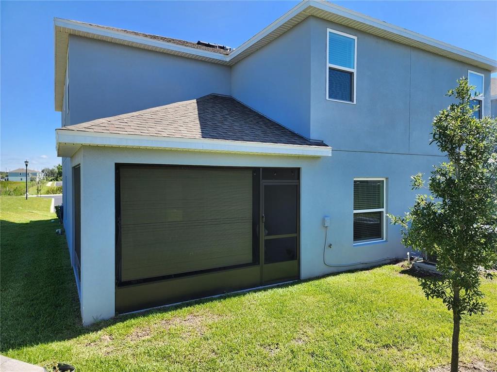 The exterior of a two-story house features a screened-in patio and a grassy yard — 474 ANNABELLE WAY, DAVENPORT, FL
