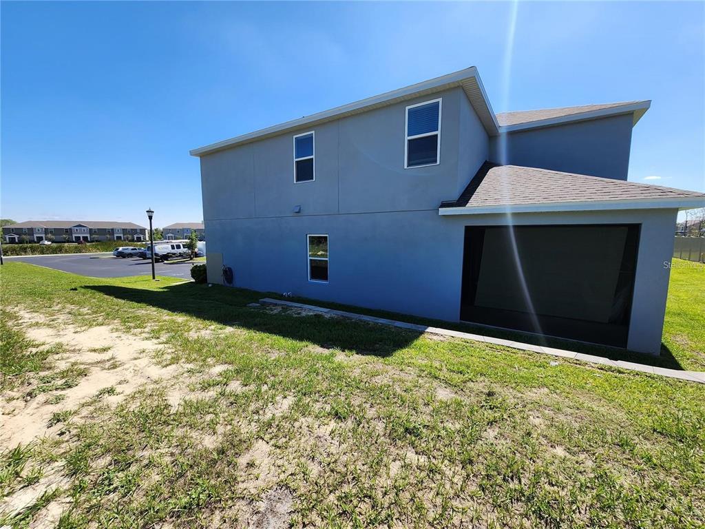 The exterior side view of a two-story house features a screened-in patio and grass yard — 474 ANNABELLE WAY, DAVENPORT, FL