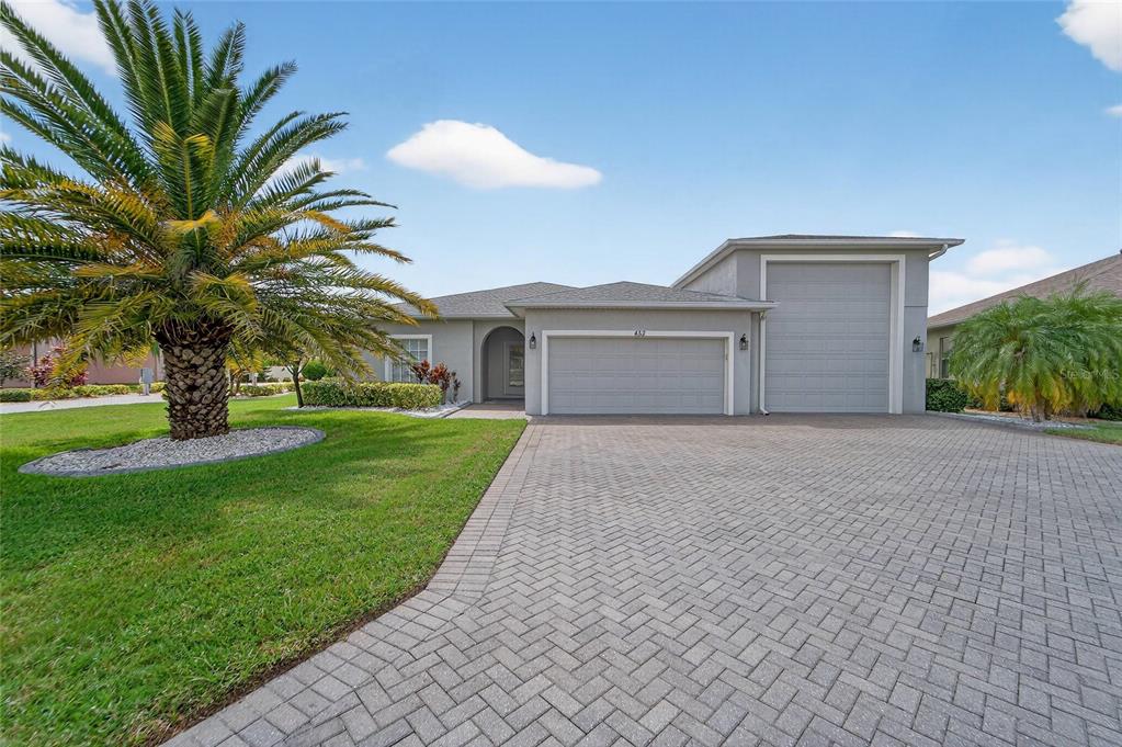 An aerial view of a gray house with a paver driveway and two garage doors — 453 NOLANE LANE, POLK CITY, FL