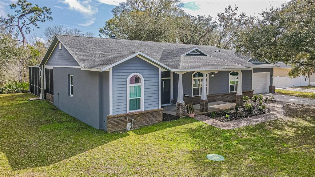 A single-story house with blue siding, a brick base, and a covered front porch — 12211 COUNT PLACE, THONOTOSASSA, FL