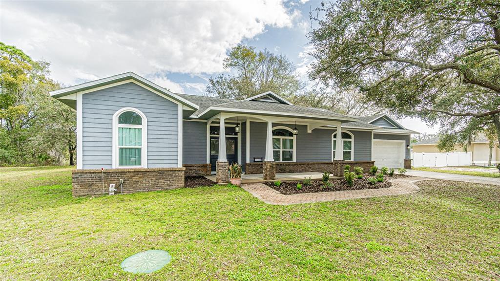 A single-story house with blue horizontal siding, brick accents, and a covered front porch — 12211 COUNT PLACE, THONOTOSASSA, FL