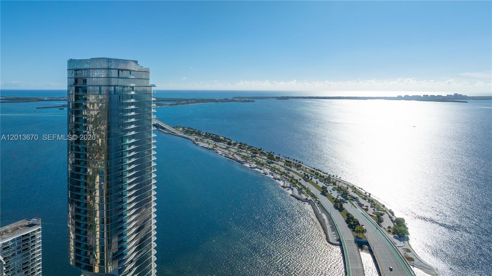 An aerial view shows a tall glass skyscraper next to a causeway over water — 175 SE 25th Rd # 4202, Miami FL 33129, MIAMI, FL