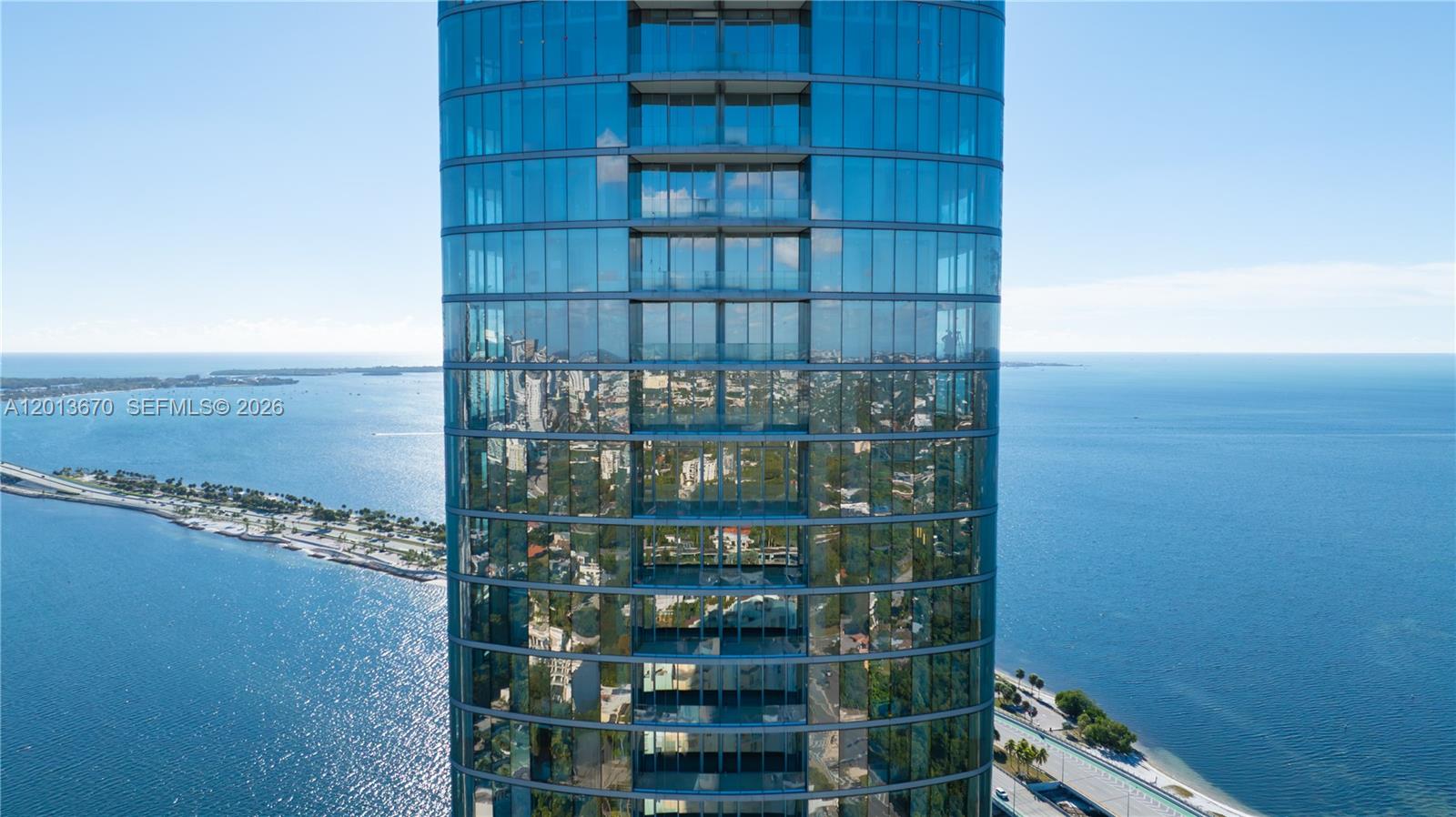 An aerial view shows the glass-clad exterior of a high-rise building overlooking the ocean — 175 SE 25th Rd # 4202, Miami FL 33129, MIAMI, FL