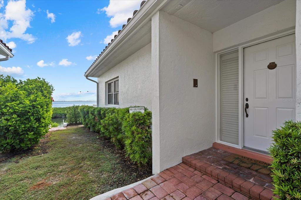 The exterior of a white house features a brick walkway leading to a front door — 2254 HARBOUR COURT DRIVE, LONGBOAT KEY, FL