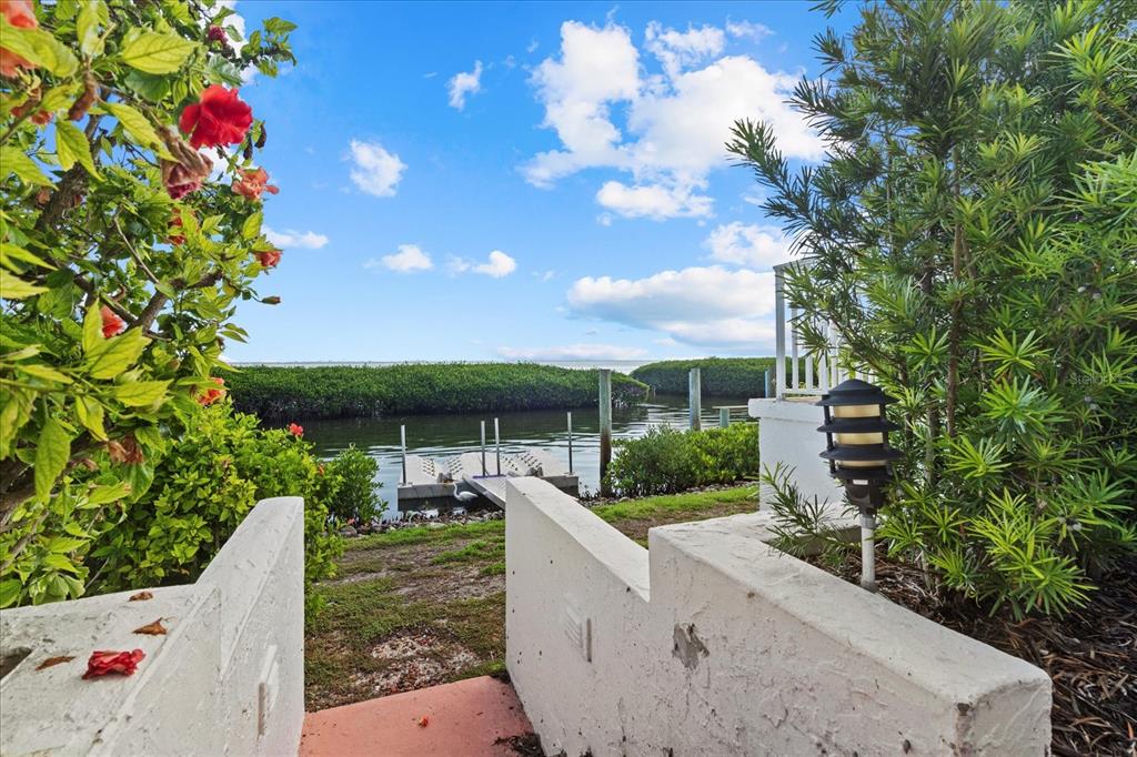 A view from a patio looking out toward a small boat dock and water — 2254 HARBOUR COURT DRIVE, LONGBOAT KEY, FL