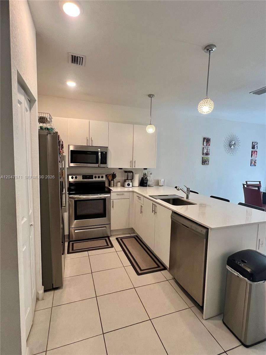 A kitchen features white cabinets, stainless steel appliances, and a peninsula with a sink — 20368 NW 4th Path, Miami Gardens FL 33169, MIAMI GARDENS, FL