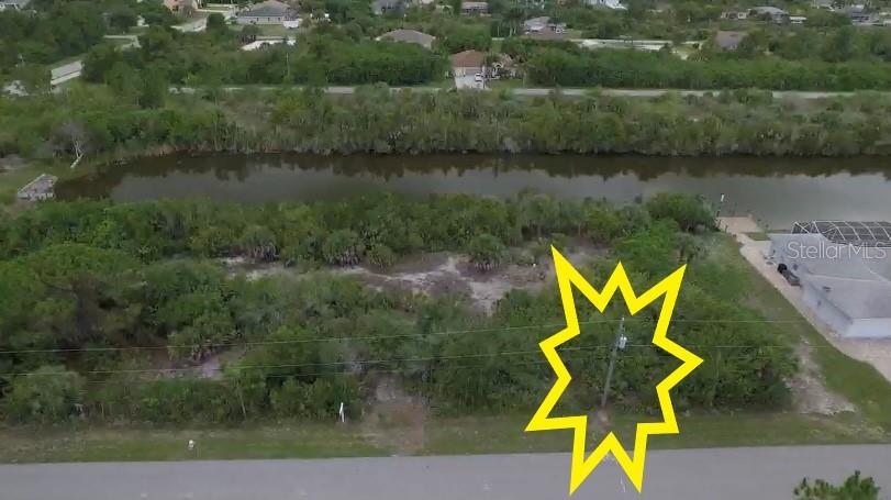 An aerial view shows a vacant, wooded lot bordering a canal with a utility pole — 15536 & 15544 HENNIPEN CIRCLE, PORT CHARLOTTE, FL