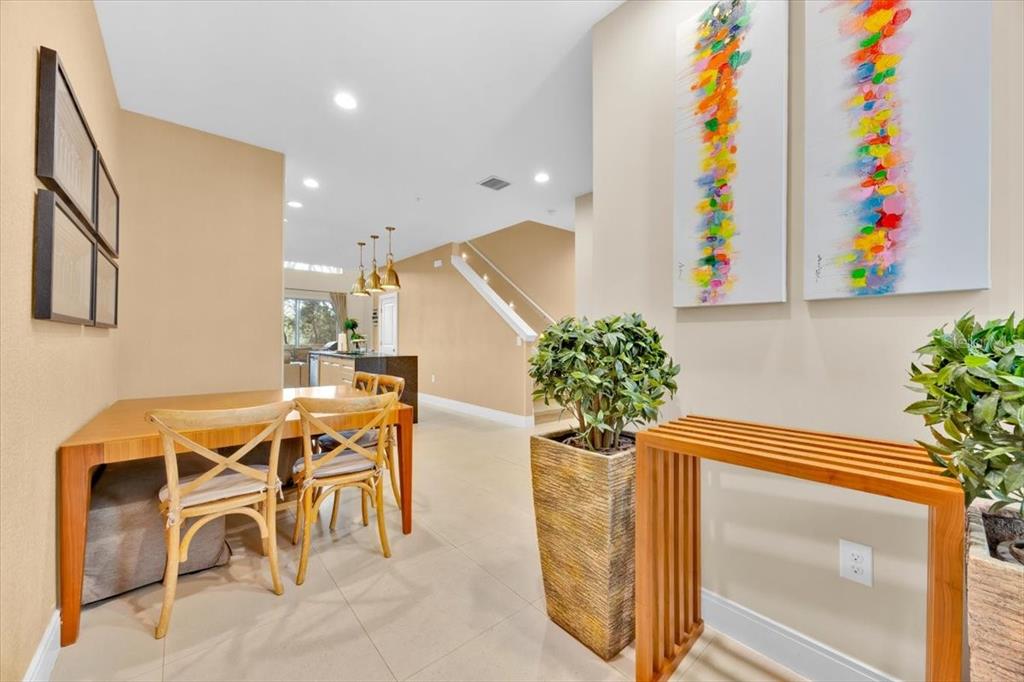 A dining area with wooden furniture, potted plants, and abstract art on a beige wall — 7663 RECIFE DRIVE, KISSIMMEE, FL