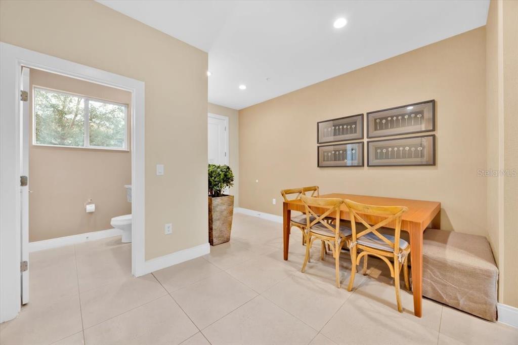 A dining area features a wooden table, four chairs, a bench, and wall art — 7663 RECIFE DRIVE, KISSIMMEE, FL