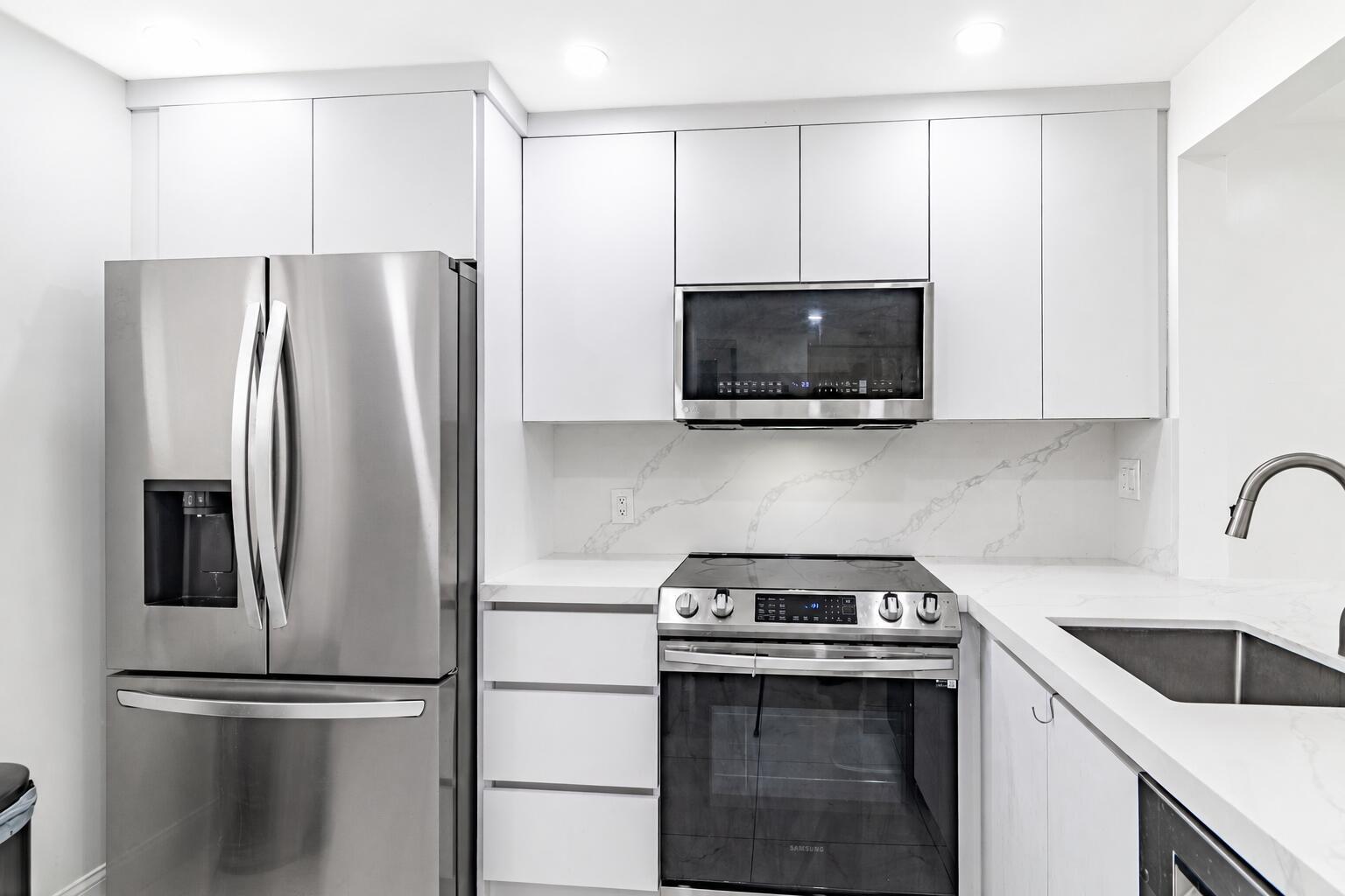 A modern kitchen features white cabinetry, stainless steel appliances, and white marble-patterned countertops — 10331 Sunrise Lakes Boulevard # 302, Sunrise FL 33322, SUNRISE, FL