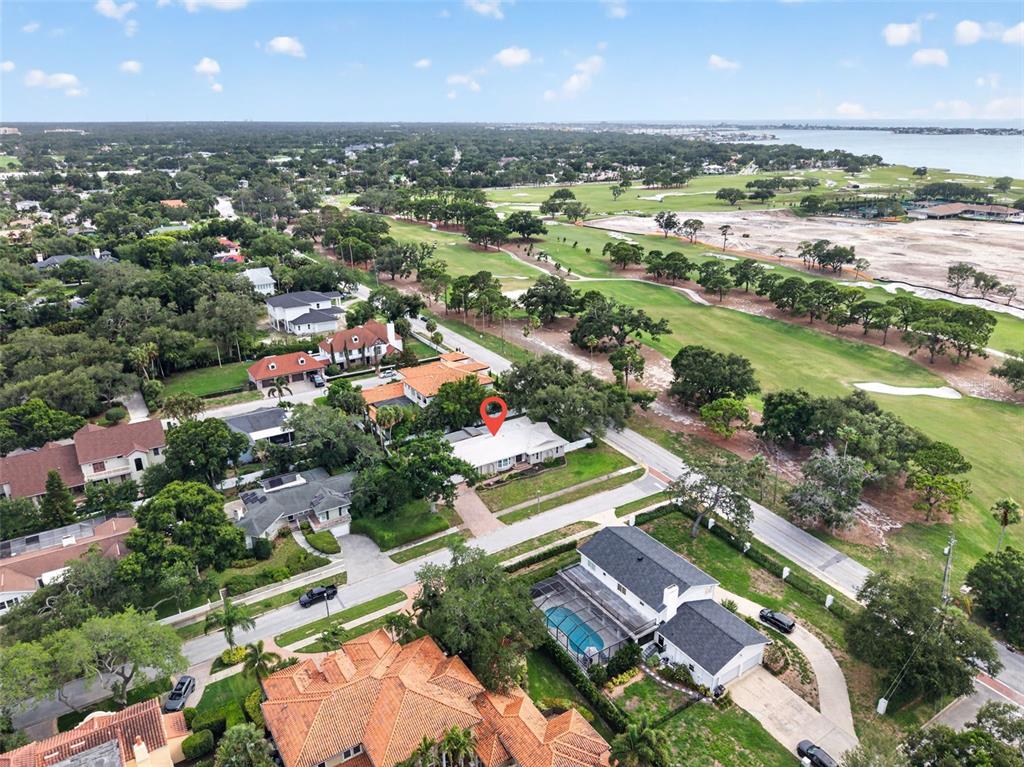 An aerial view shows a residential neighborhood with a golf course and water nearby — 303 ROEBLING ROAD S, BELLEAIR, FL