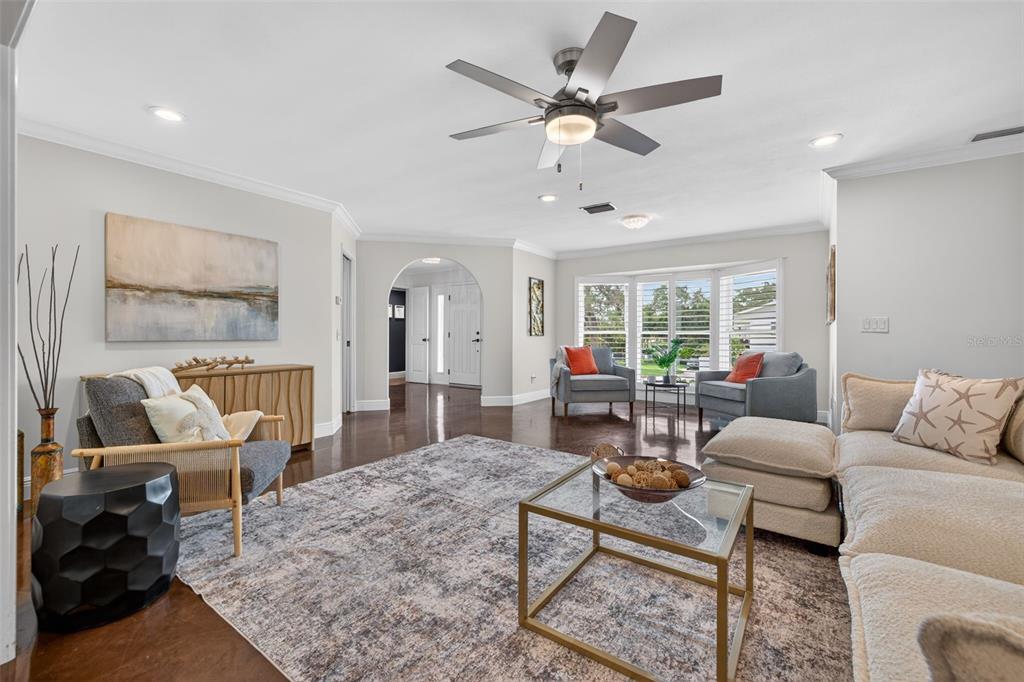 A living room features a ceiling fan, a large area rug, and a sectional sofa — 303 ROEBLING ROAD S, BELLEAIR, FL