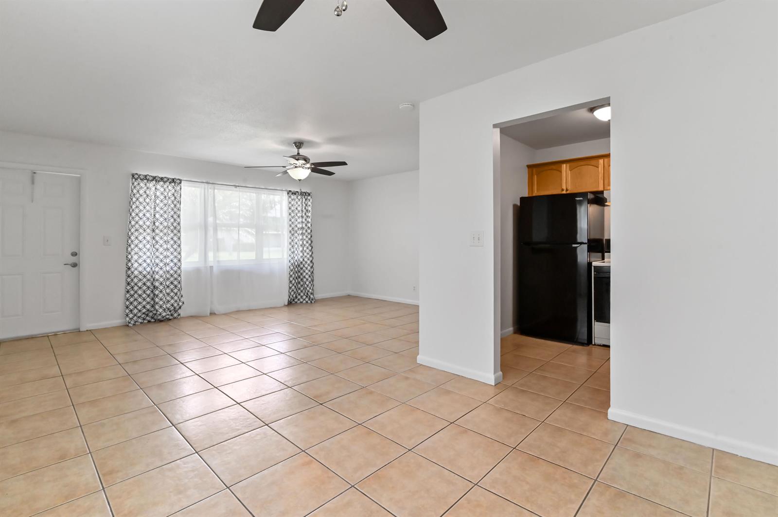 An open-concept living area with tile flooring, a ceiling fan, and an adjacent kitchen — 149 Coventry # G, West Palm Beach FL 33417, WEST PALM BEACH, FL