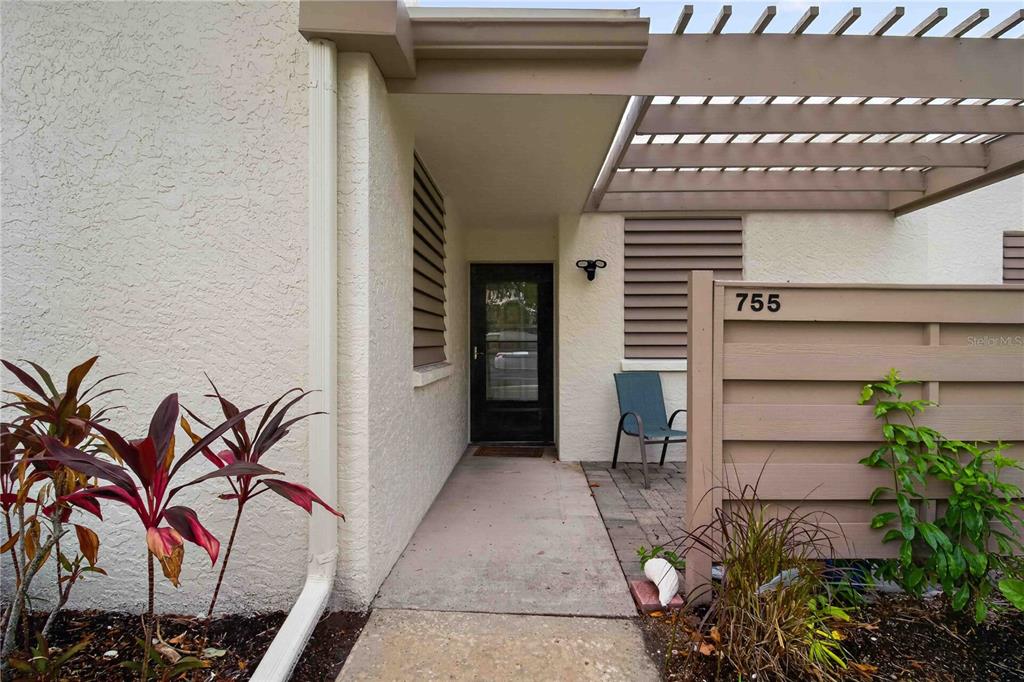 The exterior entrance features a paved walkway, a wooden privacy fence, and a pergola overhead — 755 OAKVIEW DRIVE, BRADENTON, FL