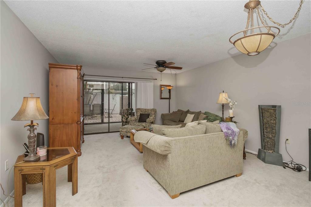 A living room features light carpeting, a ceiling fan, a sliding glass door, and furniture — 755 OAKVIEW DRIVE, BRADENTON, FL