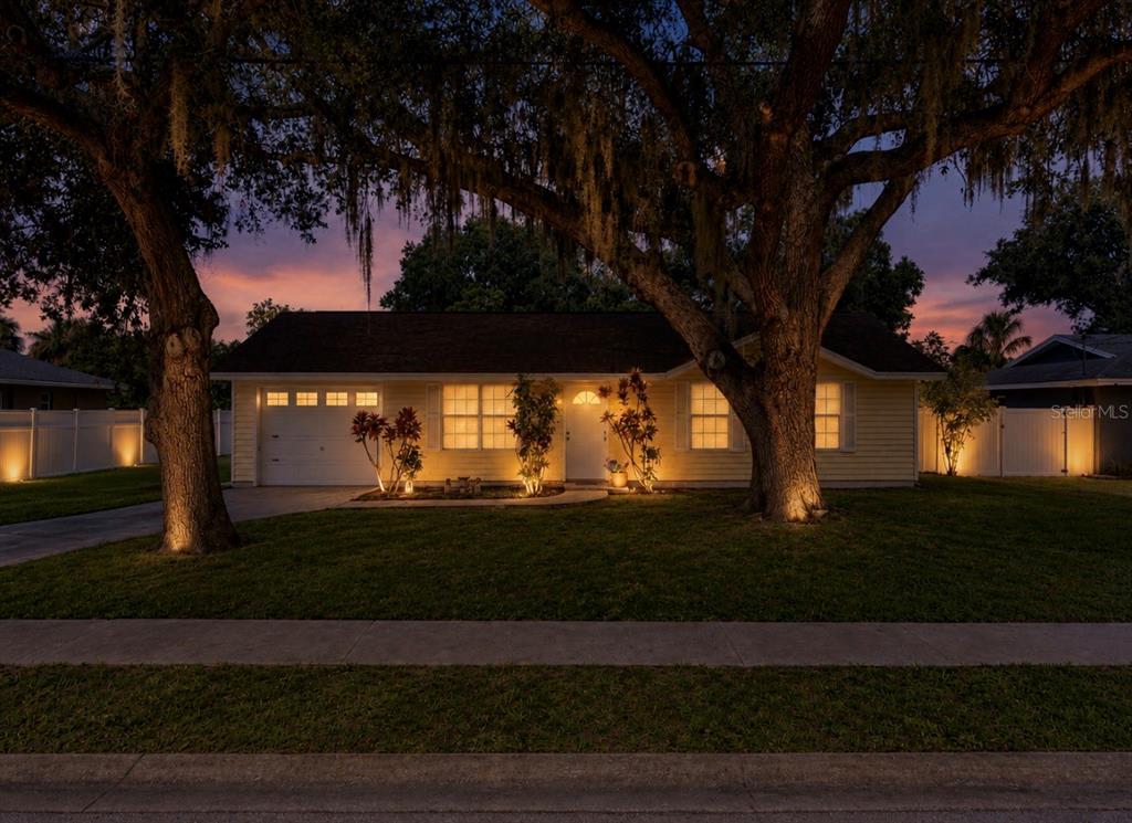 A single-story yellow house with a garage and large trees at dusk — 2336 JAVA PLUM AVENUE, SARASOTA, FL