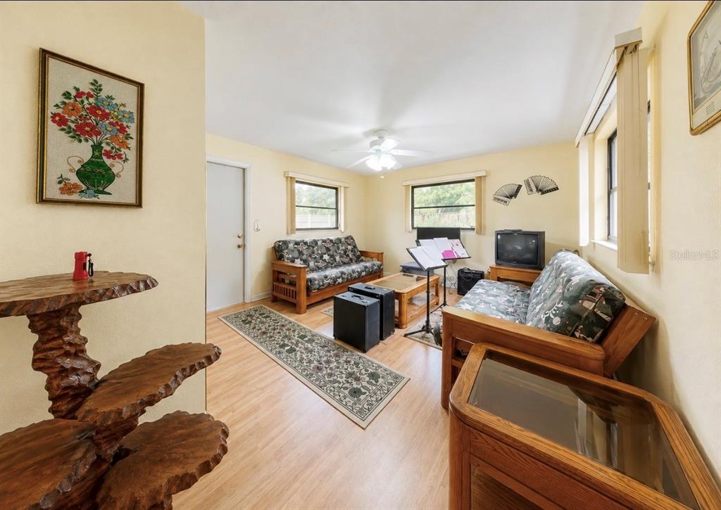 A living room with light yellow walls, wood-look flooring, two futons, and a wooden stand — 2336 JAVA PLUM AVENUE, SARASOTA, FL