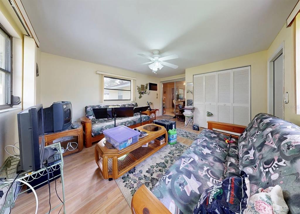 A living room features two futons, a wooden coffee table, a television, and light flooring — 2336 JAVA PLUM AVENUE, SARASOTA, FL