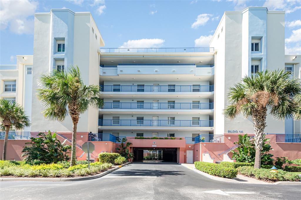 A multi-story apartment building with a central parking garage entrance and palm trees in front — 5300 S ATLANTIC AVENUE UNIT 14-205, NEW SMYRNA BEACH, FL