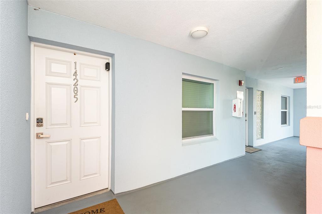 A white door with the number 14205 leads to a covered outdoor hallway with light walls — 5300 S ATLANTIC AVENUE UNIT 14-205, NEW SMYRNA BEACH, FL