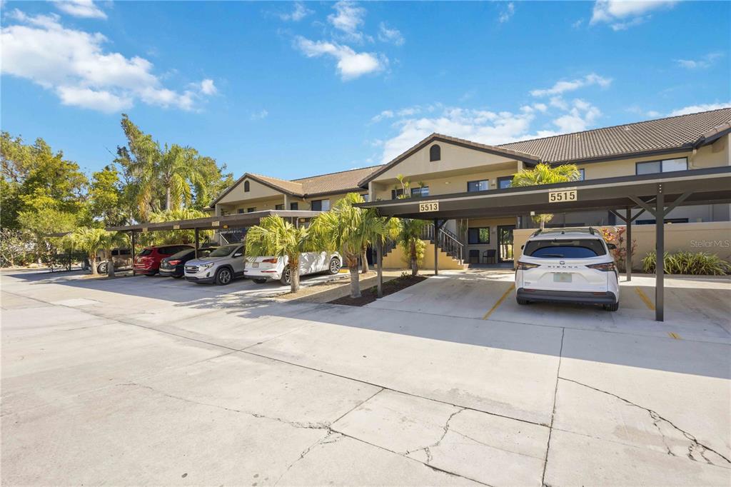 A multi-unit residential building features covered parking spaces and a concrete driveway — 5515 ASHTON WAY UNIT 5515, SARASOTA, FL