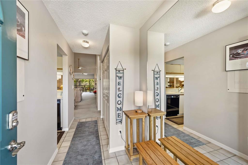 An entryway with tile flooring, a wooden bench, a mirror, and a welcome sign — 5515 ASHTON WAY UNIT 5515, SARASOTA, FL