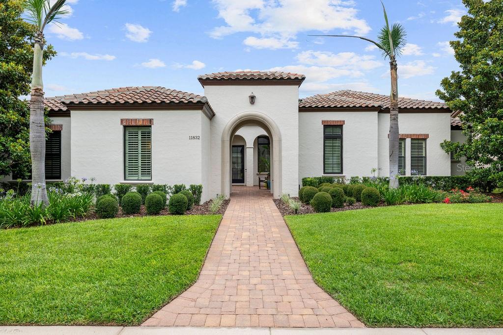 A single-story stucco house with a tiled roof, arched entryway, and a brick walkway — 11832 WATERSTONE LOOP DRIVE, WINDERMERE, FL