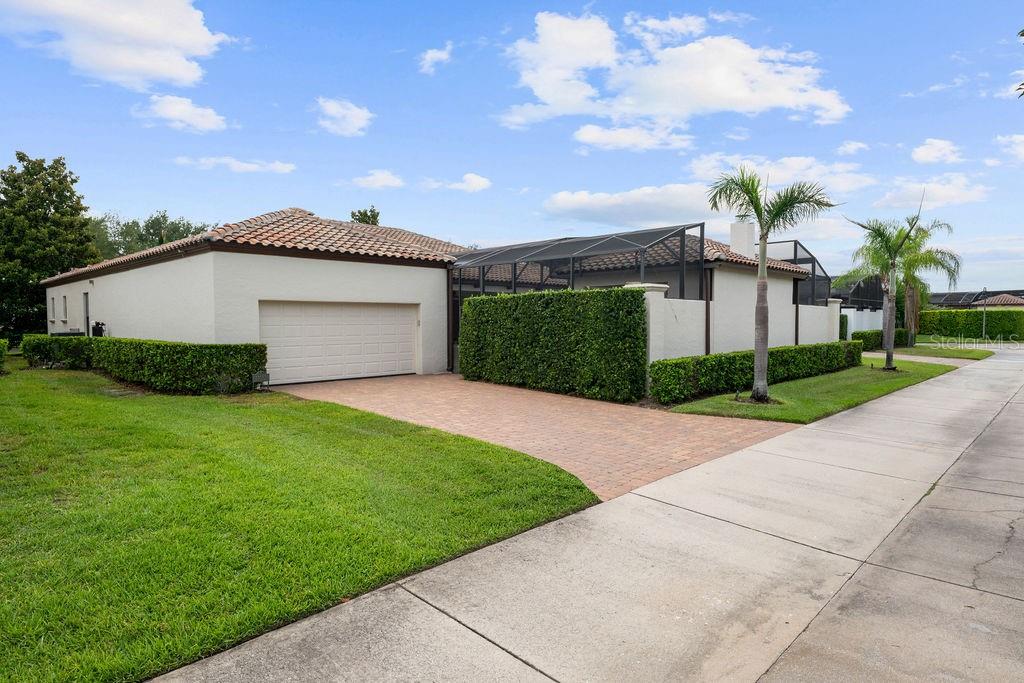 A single-story house with a tiled roof, a brick driveway, and a screened-in patio area — 11832 WATERSTONE LOOP DRIVE, WINDERMERE, FL