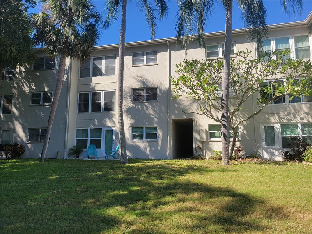 A three-story apartment building exterior with palm trees and a grassy lawn in front — 841 PATRICIA AVENUE UNIT 206, DUNEDIN, FL