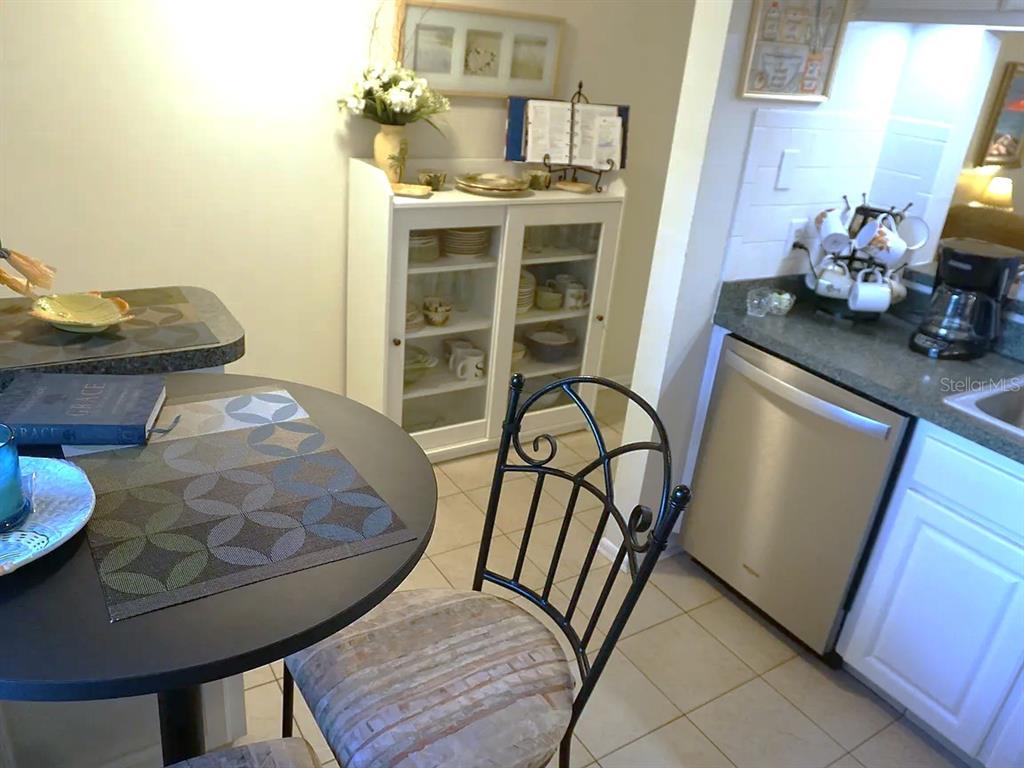 A small dining area features a round table, a white hutch, and an adjacent kitchen — 841 PATRICIA AVENUE UNIT 206, DUNEDIN, FL