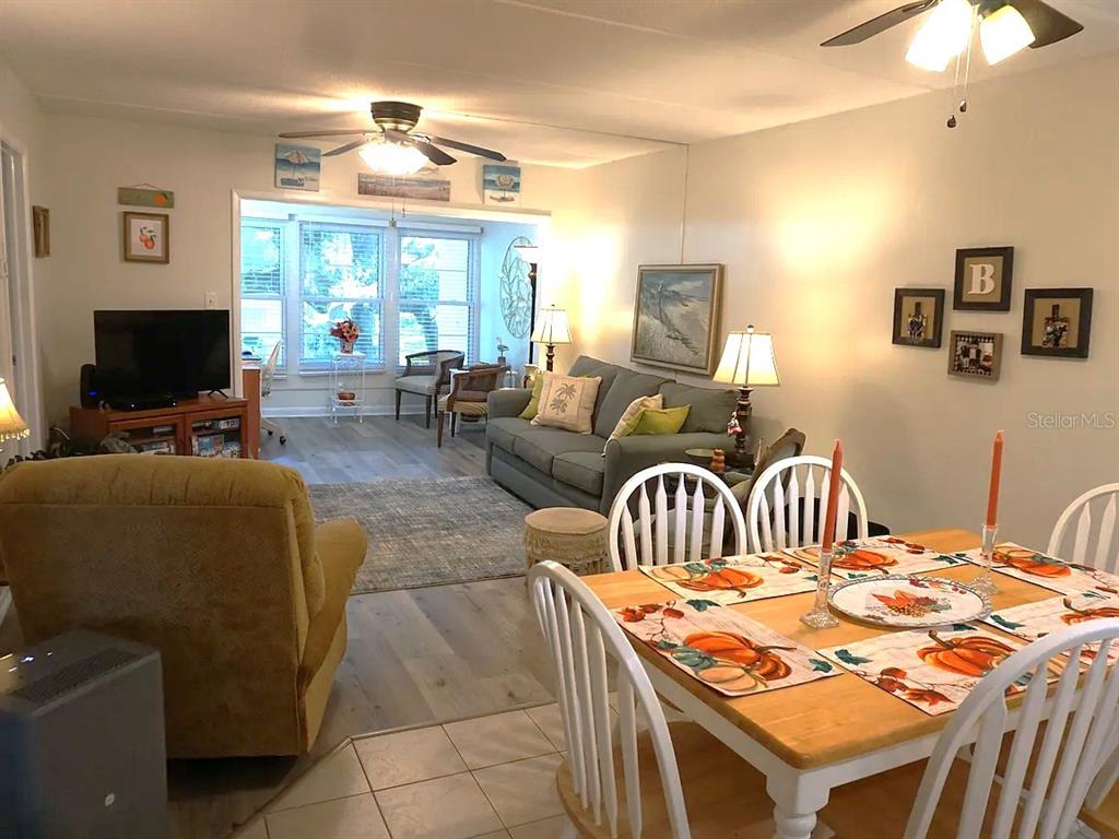 A dining area with a wooden table leads into a living room with a sofa — 841 PATRICIA AVENUE UNIT 206, DUNEDIN, FL
