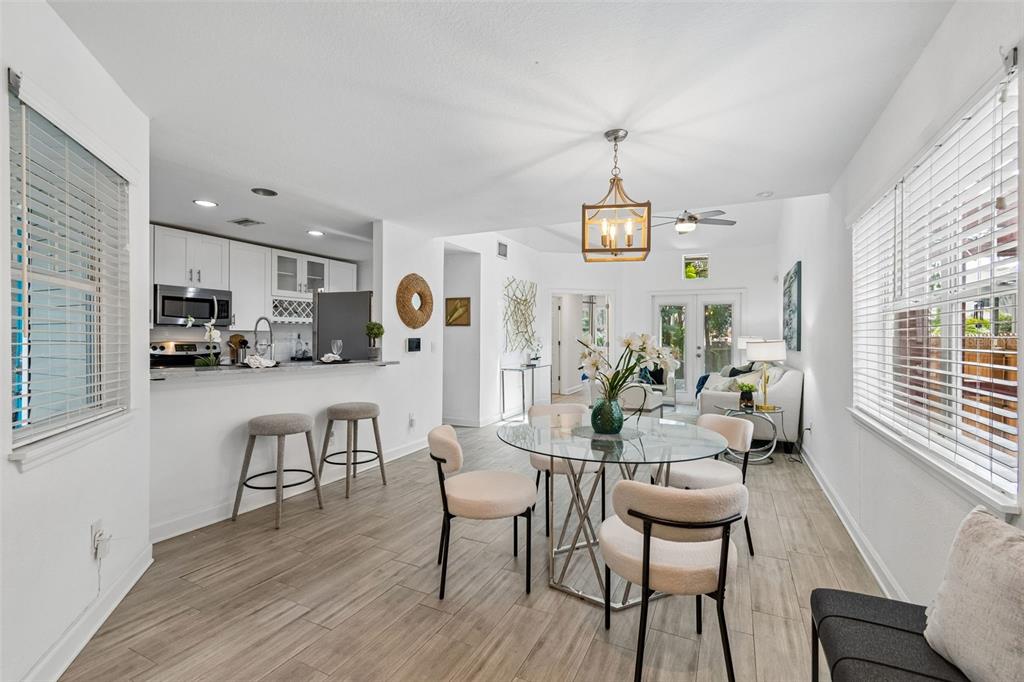 A bright, open-concept dining area with a glass table, bar seating, and light wood flooring — 4418 W NORTH B STREET, TAMPA, FL