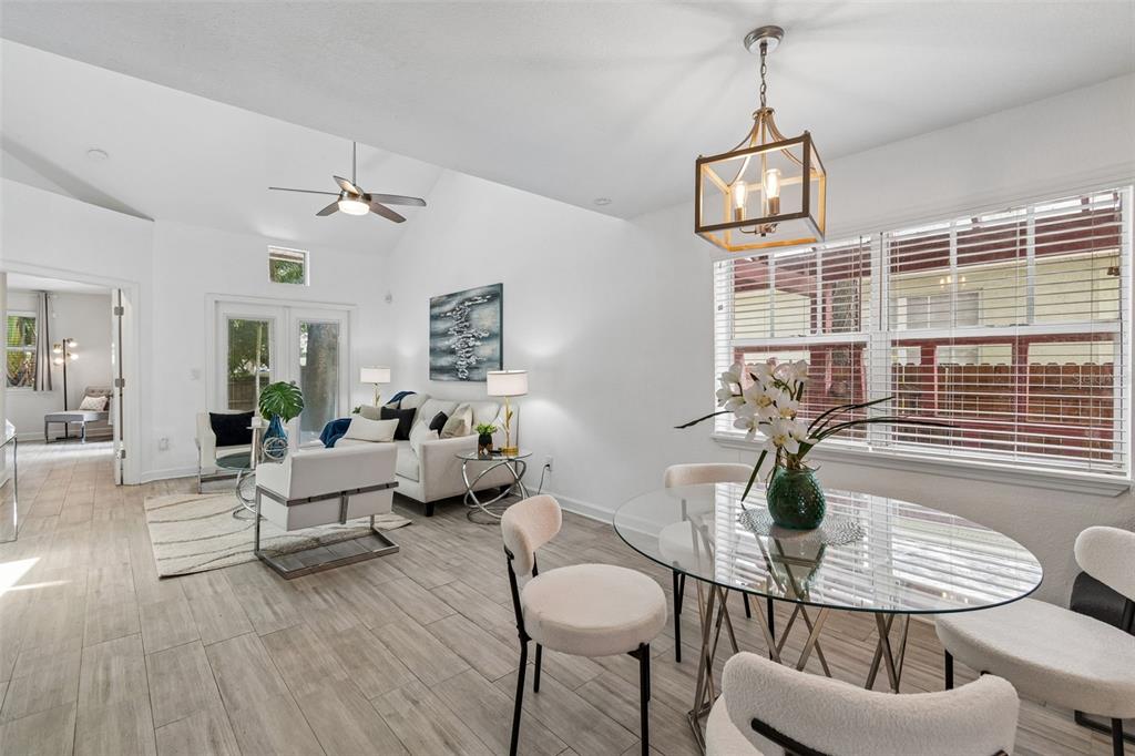 A bright living and dining area features white walls, tile flooring, and a glass table — 4418 W NORTH B STREET, TAMPA, FL
