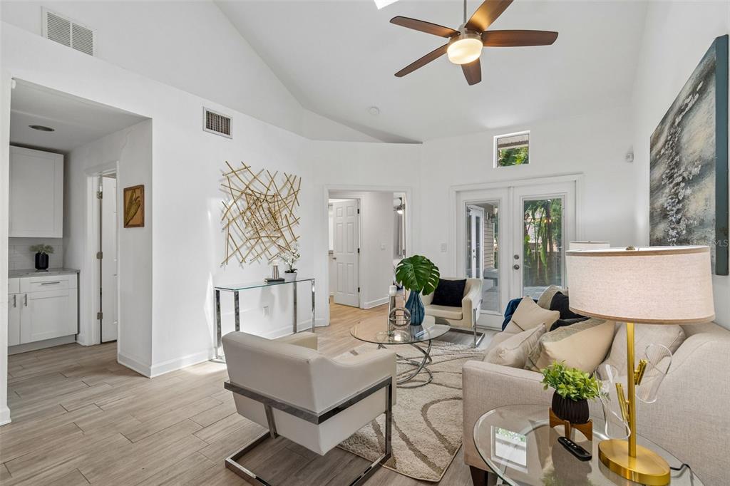 A bright living room features vaulted ceilings, tile floors, a ceiling fan, and glass doors — 4418 W NORTH B STREET, TAMPA, FL