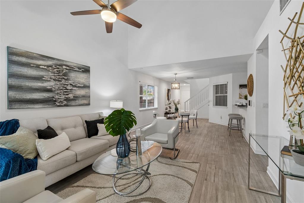A bright living room features a vaulted ceiling, light wood-look tile floors, and modern furniture — 4418 W NORTH B STREET, TAMPA, FL