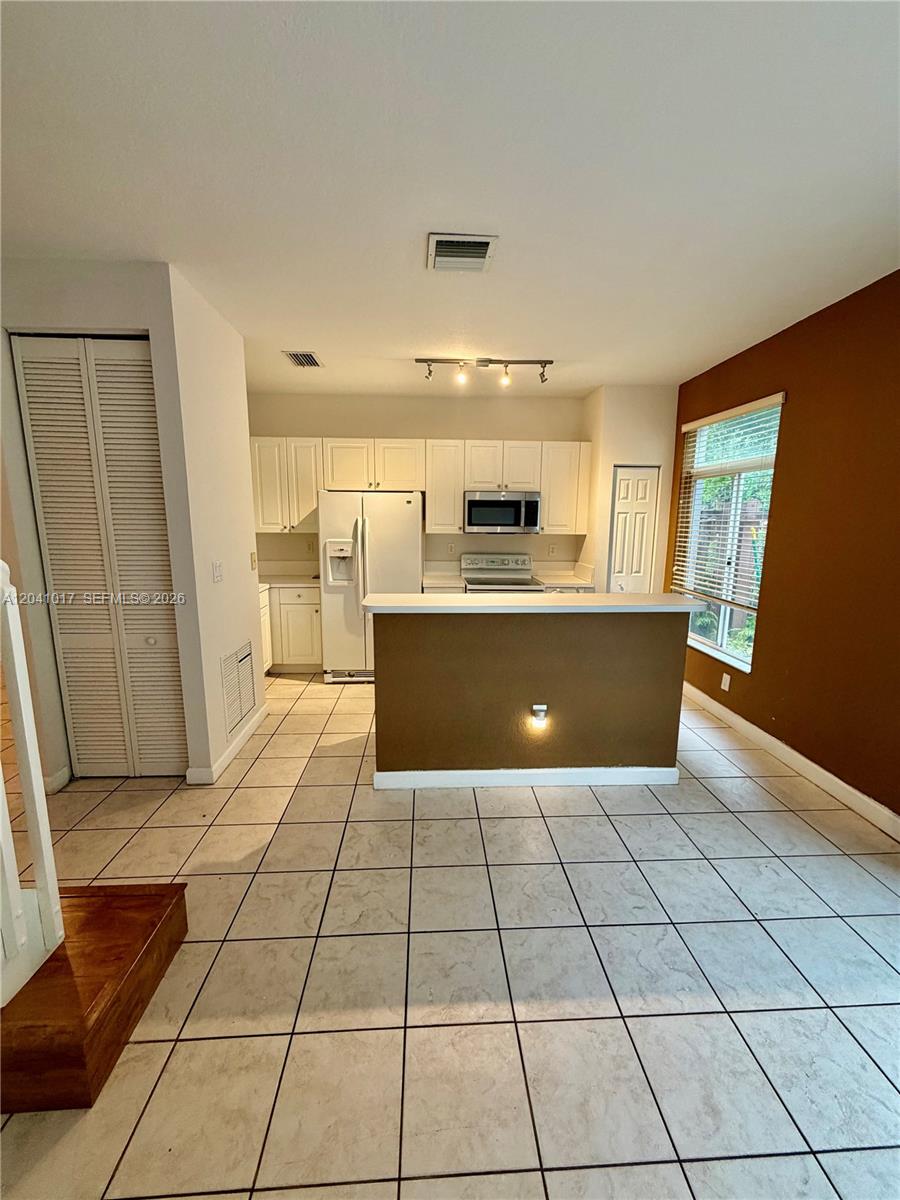 A kitchen features white cabinets, stainless steel appliances, and a brown breakfast bar island — 5770 NW 113th Pl, Doral FL 33178, DORAL, FL