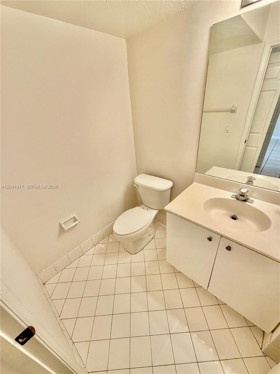 A small bathroom features a white vanity, a toilet, and light-colored diagonal floor tiles — 5770 NW 113th Pl, Doral FL 33178, DORAL, FL