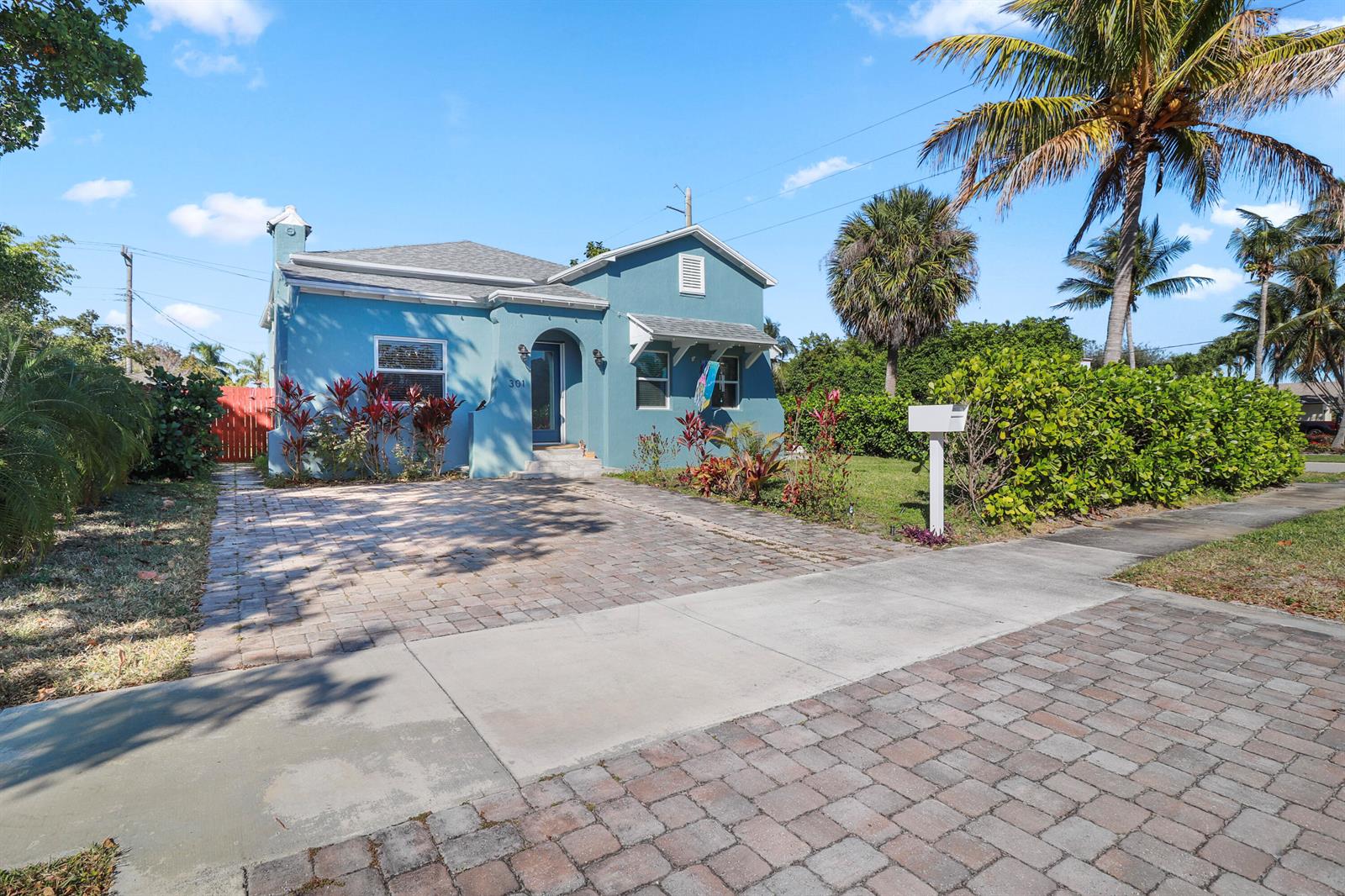 A blue single-story house with a brick driveway and a palm tree in the yard — 301 Hawthorne Drive, Lake Park FL 33403, LAKE PARK, FL